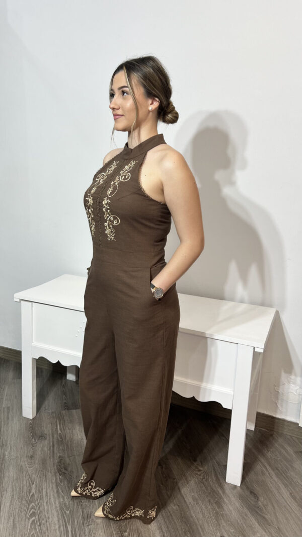 Mujer vistiendo un elegante mono marrón sin mangas con detalles bordados florales, disponible en la tienda online Arezzo de moda y complementos de mujer, ideal para un look sofisticado y moderno.